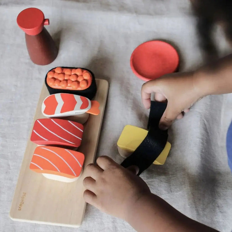 
                    
                      PlanToys Sushi Set, wooden play set with salmon, tuna, tamago, shrimp, roe, tray, and shoyu bottle on a white background
                    
                  