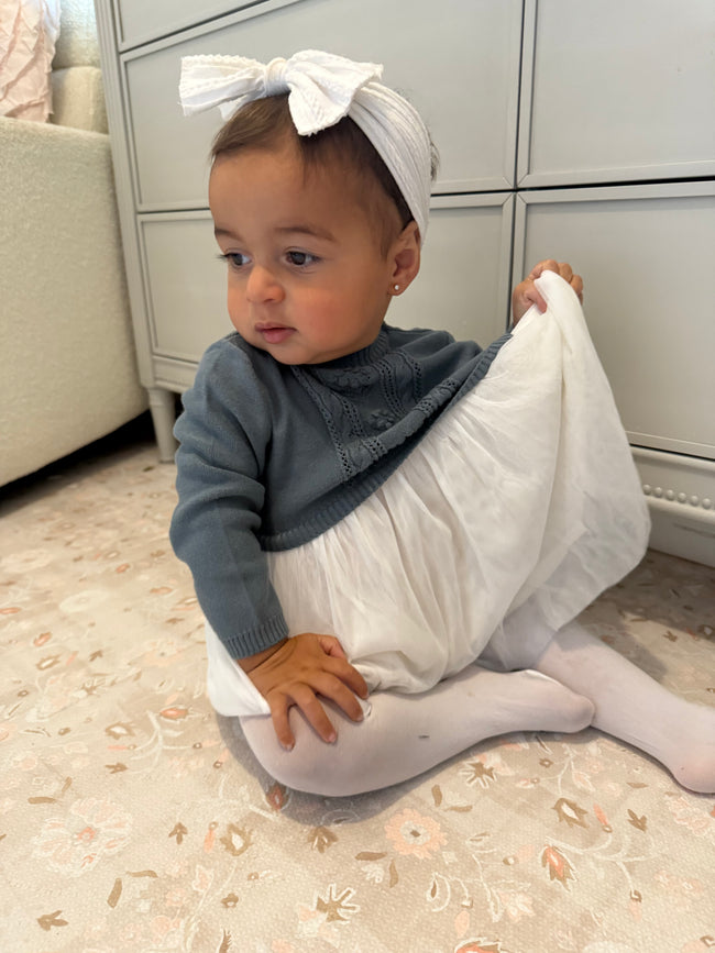 baby girl sitting wearing blues baby sweater dress