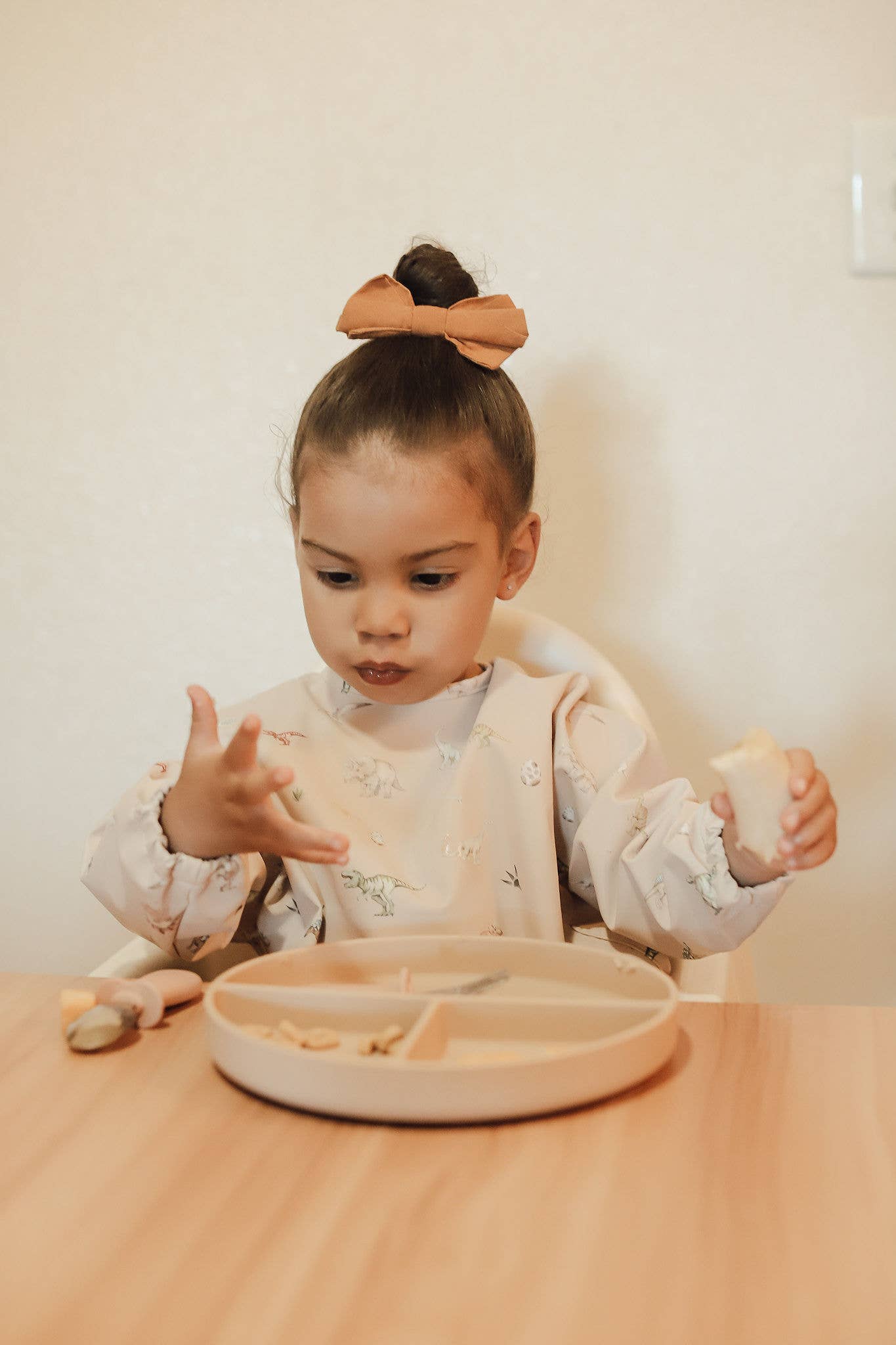 aby wearing Ali + Oli dino print smock bib set during feeding time