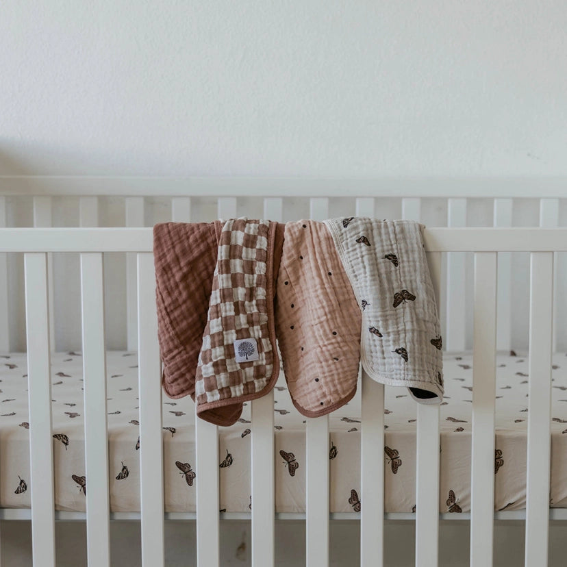 Oversized baby burp cloth from The Flutter Pack on parent’s shoulder