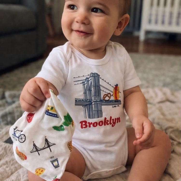 Brooklyn Buddies Organic Baby Bodysuit by Estella, hot dog and pretzel characters walking the Brooklyn Bridge in soft organic cotton with snap closures
