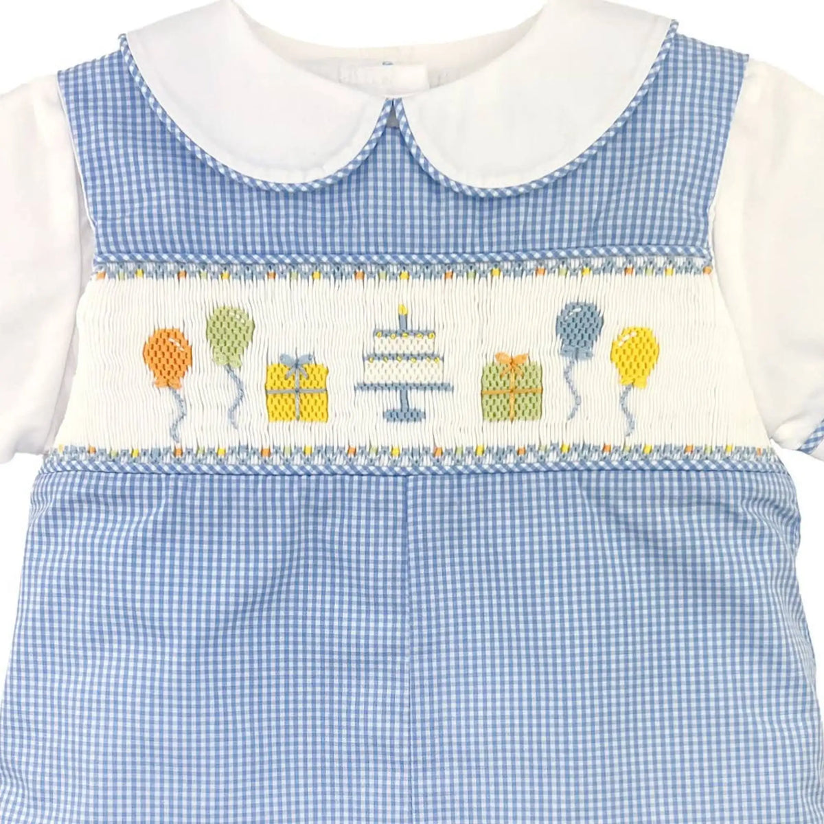 A baby boy's short-sleeve smocked romper in light blue and white gingham, featuring a white Peter Pan collar, white smocked chest panel with embroidered balloons and a cake, and blue piping details.